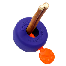 Load image into Gallery viewer, A purple Bully Grip BullyLok toy with two chew sticks inserted into the center and an orange paw-shaped treat dispenser attached, shown on a plain white background. The toy is branded 'Bully' and 'Bully Grip'.